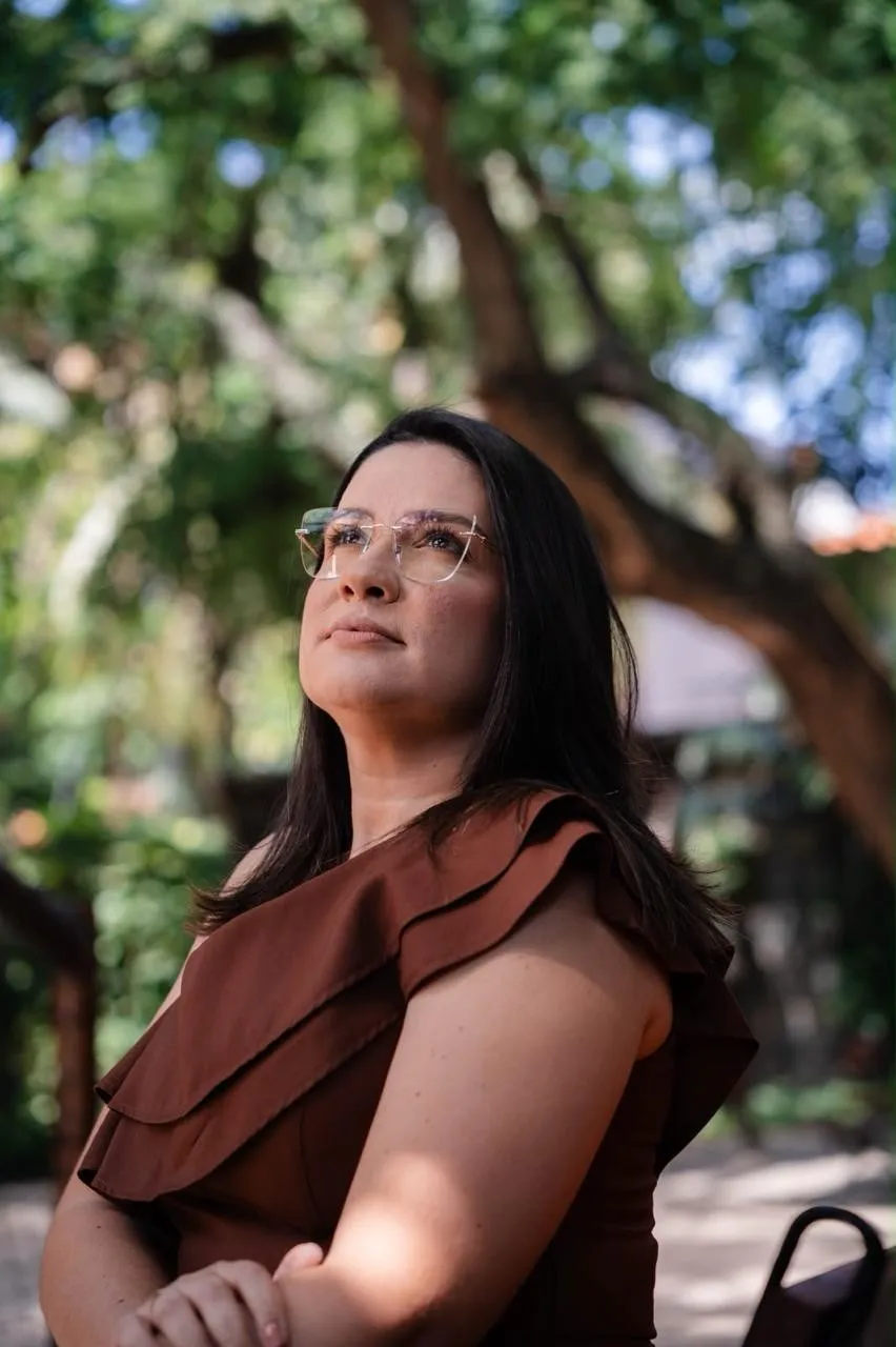 Dra. Camilla Arouca olhando para o alto, entre as árvores
