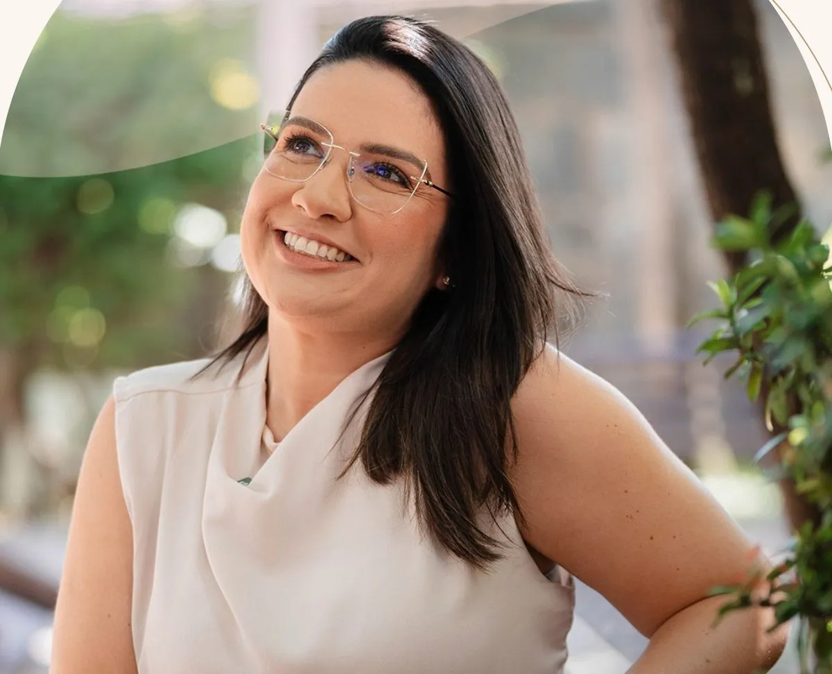 Dra. Camilla Arouca, pediatra, sorrindo em um jardim